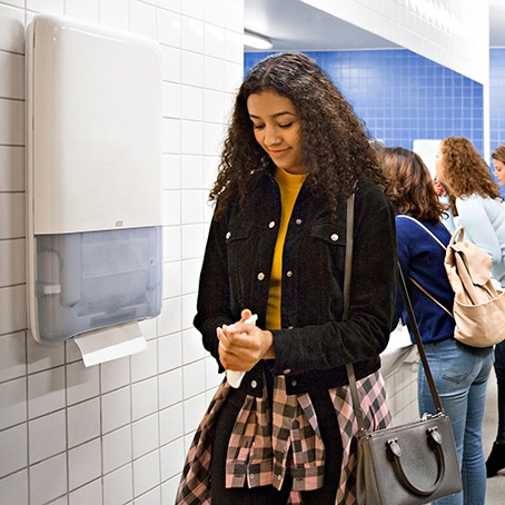 Woman using hand towels in restroom