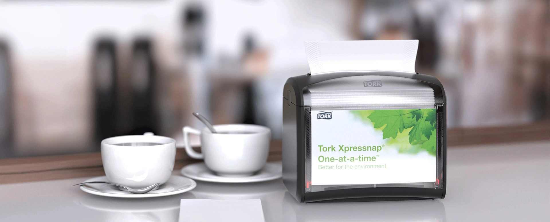 Tork napkins dispenser sitting on table with two cups of coffee