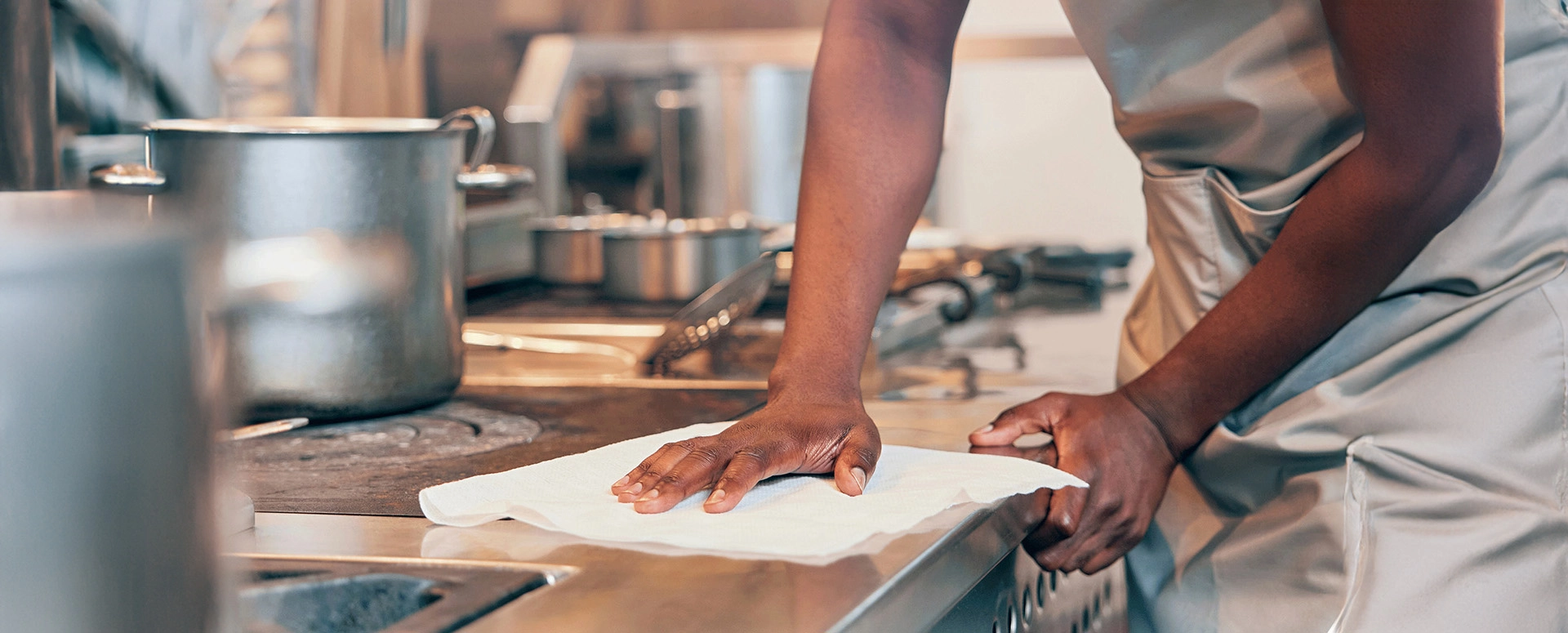 Commercial kitchen stove with cook wiping down surfaces